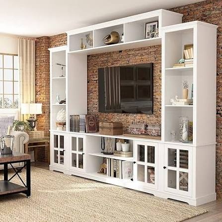A styled living room with a white entertainment center against a brick wall